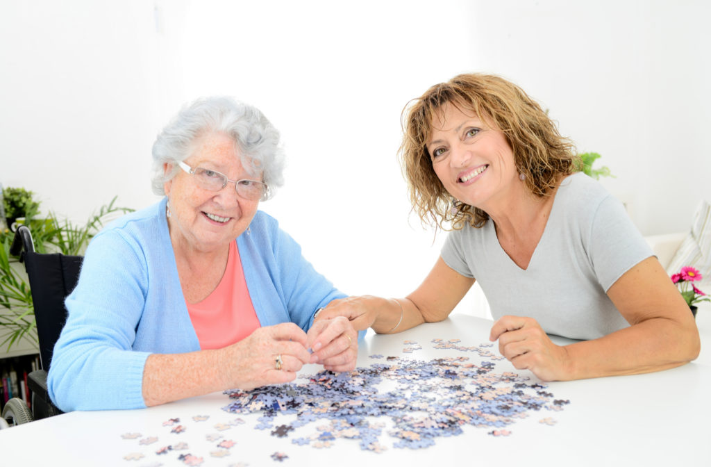 Happy senior women along side nurse working on memory care activities in senior community