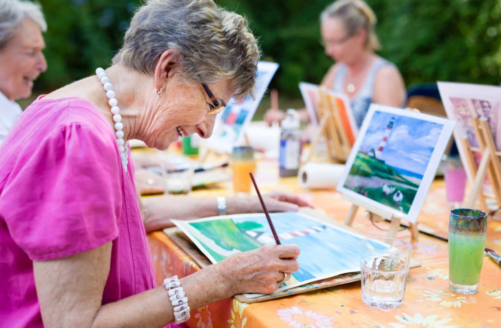 A elderly woman enjoying a painting session at minnehaha senior living community.