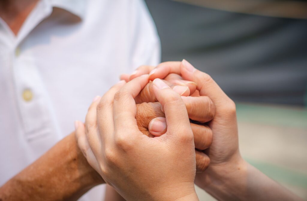 Close-up of senior hands being gently held, showing care and support.