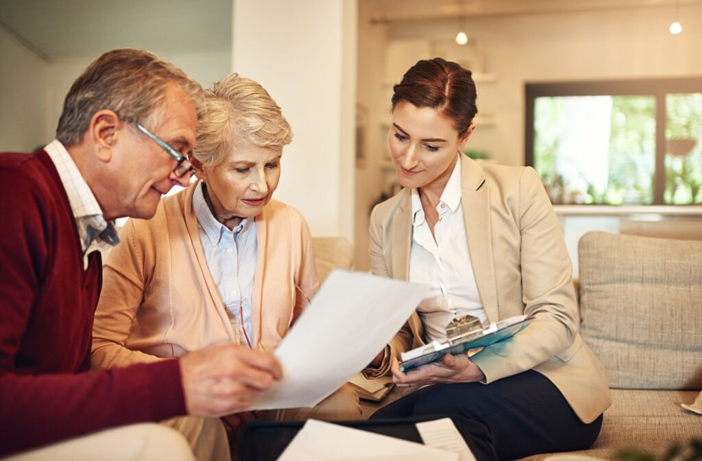 A representative of a senior living community checks paperwork while an older couple reads through application forms